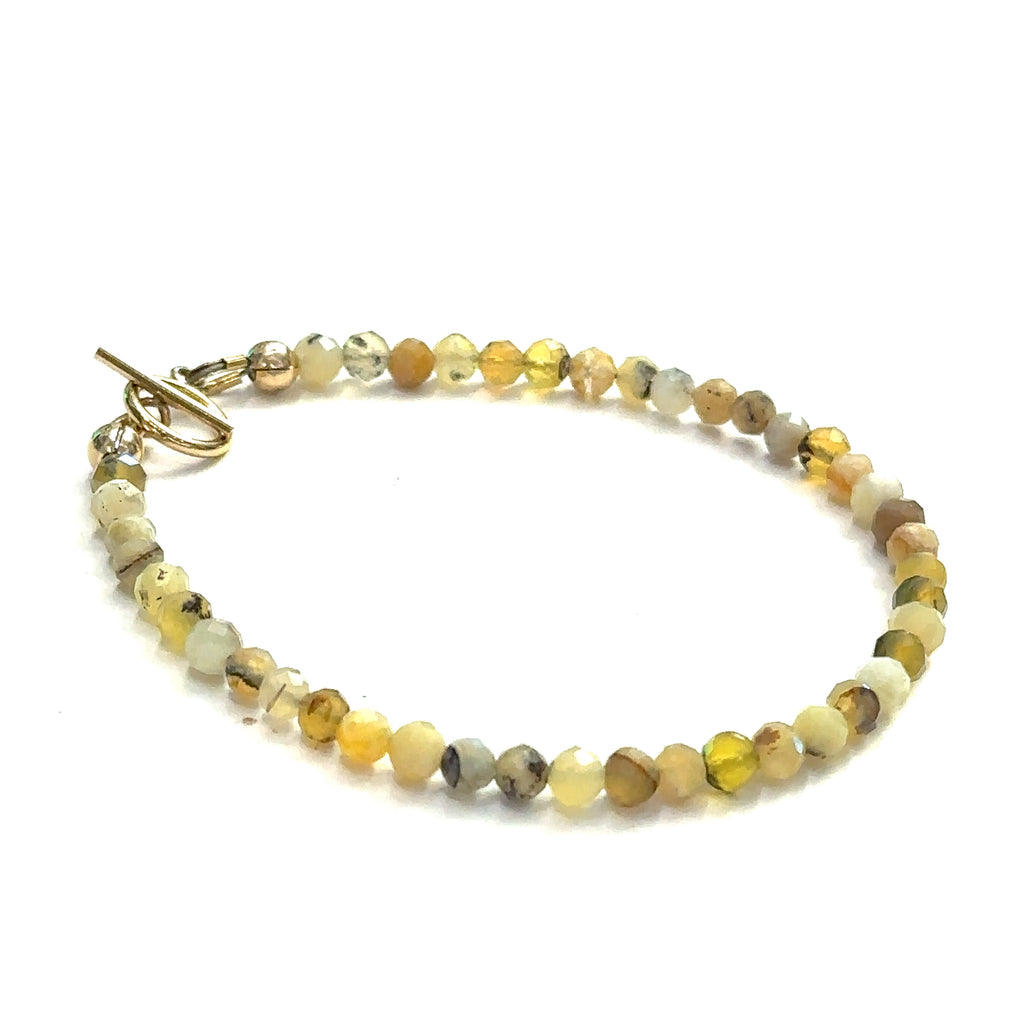 Close-up of 4mm faceted Yellow Opal beads showing natural yellow tones on a white background, right side view