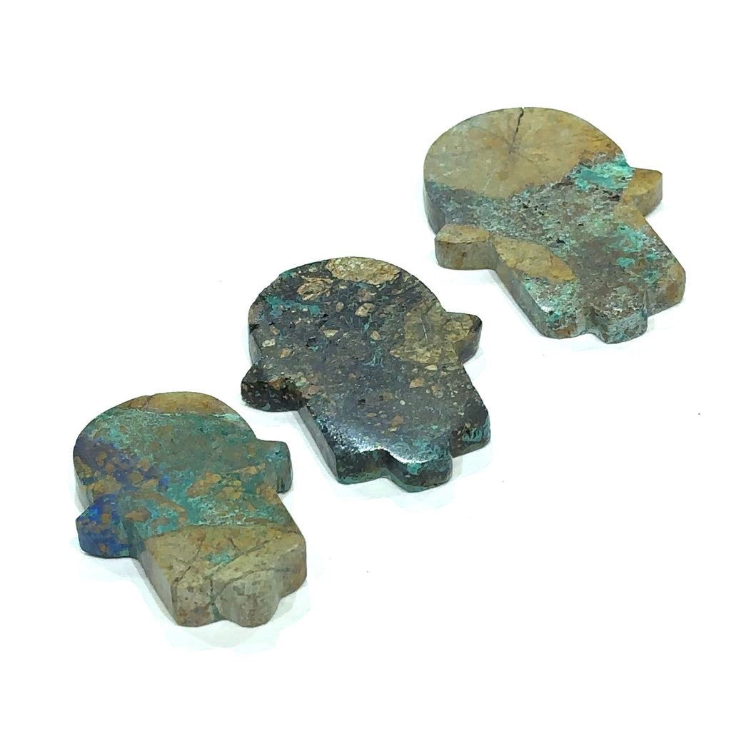 Close-up of Azurite Malachite Hamsa showing natural color variations in models hand on white background front view.