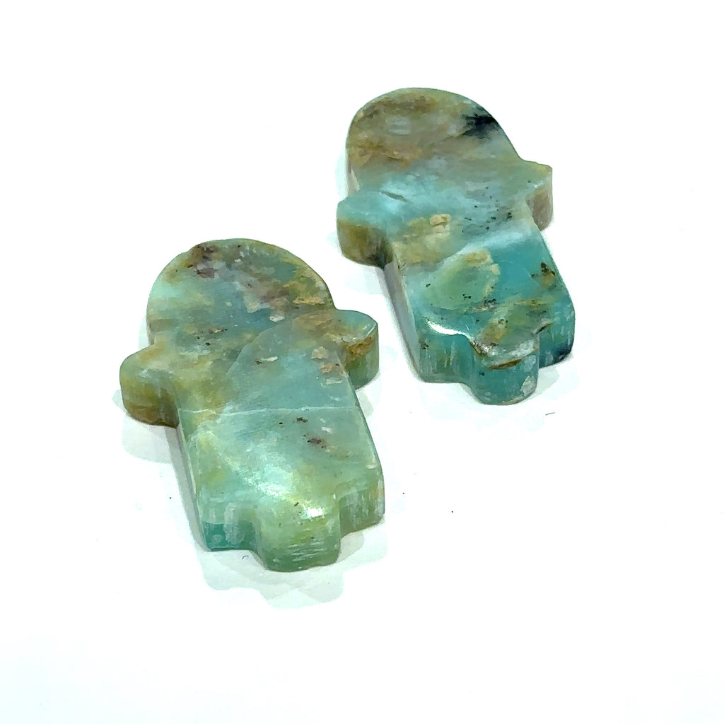 Close-up of Blue Opal Hamsa showing natural color variations in models hand on white background front view.