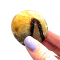 Close-up of Septarian stone texture and color detail on a white background in a models hand for a close up view. 