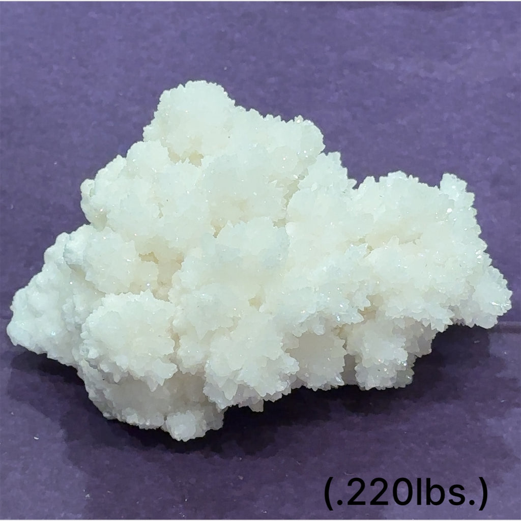 Close-up of White Aragonite cluster highlighting natural white crystal formations size (.220lbs.) on purple background front view.