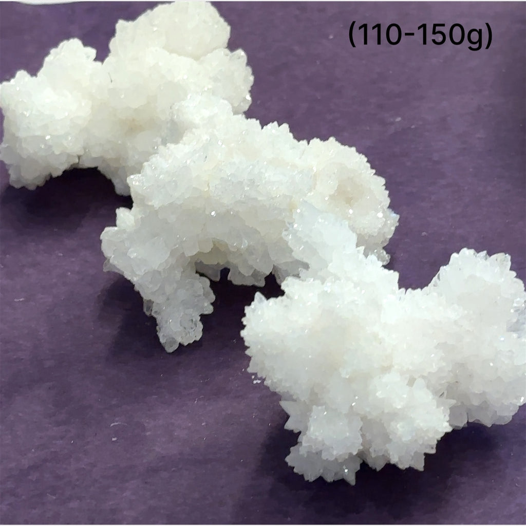 Close-up of White Aragonite cluster highlighting natural white crystal formations size (110-150g) on purple background front view.