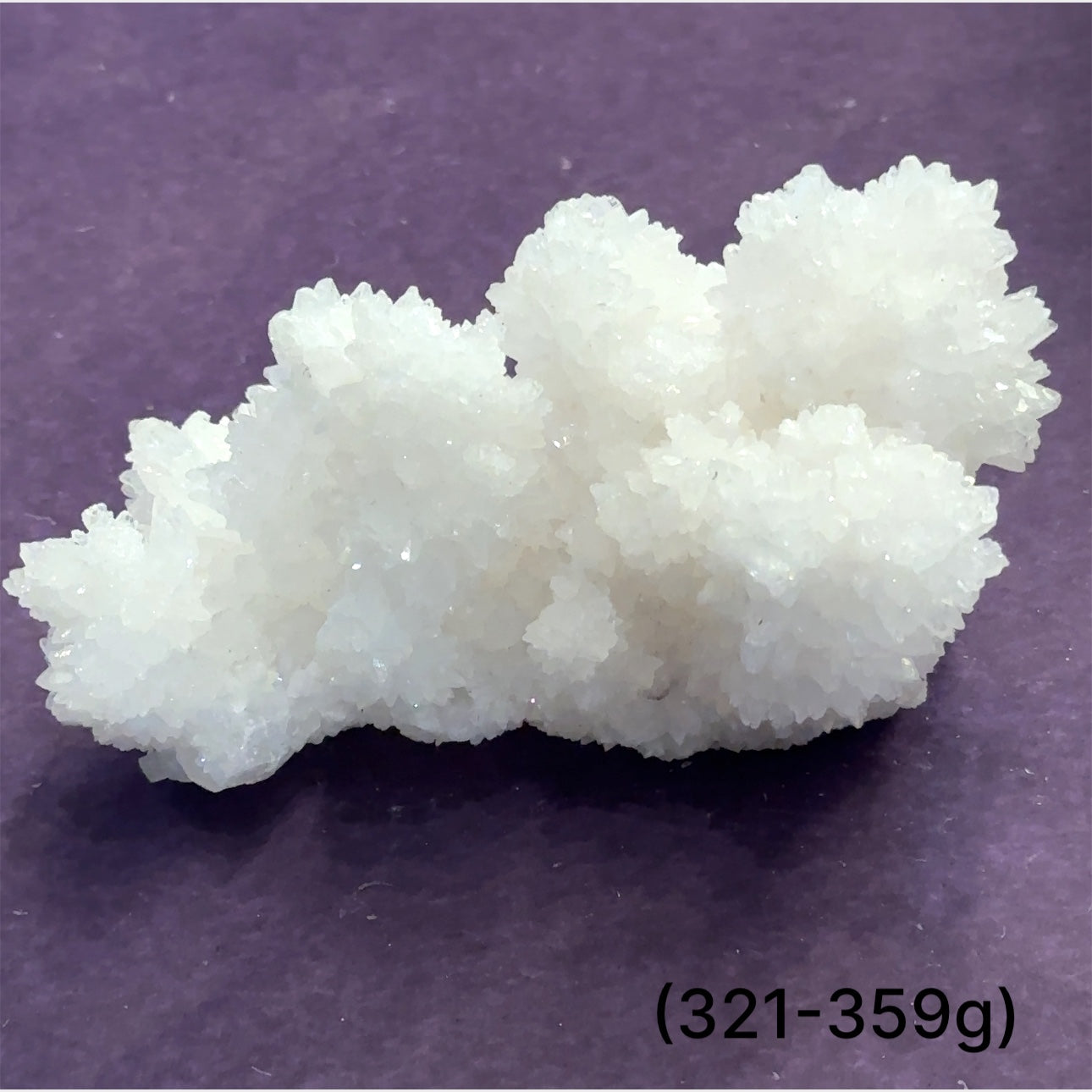 Close-up of White Aragonite cluster highlighting natural white crystal formations size (321-359g) on purple background front view.