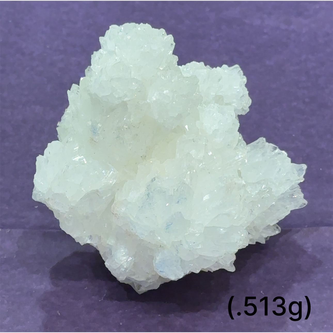 Close-up of White Aragonite cluster highlighting natural white crystal formations size (513g) on purple background front view.
