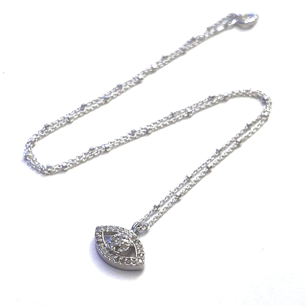 Close-up of diamond Evil Eye charm showing sparkle and silver details on a white background center overview