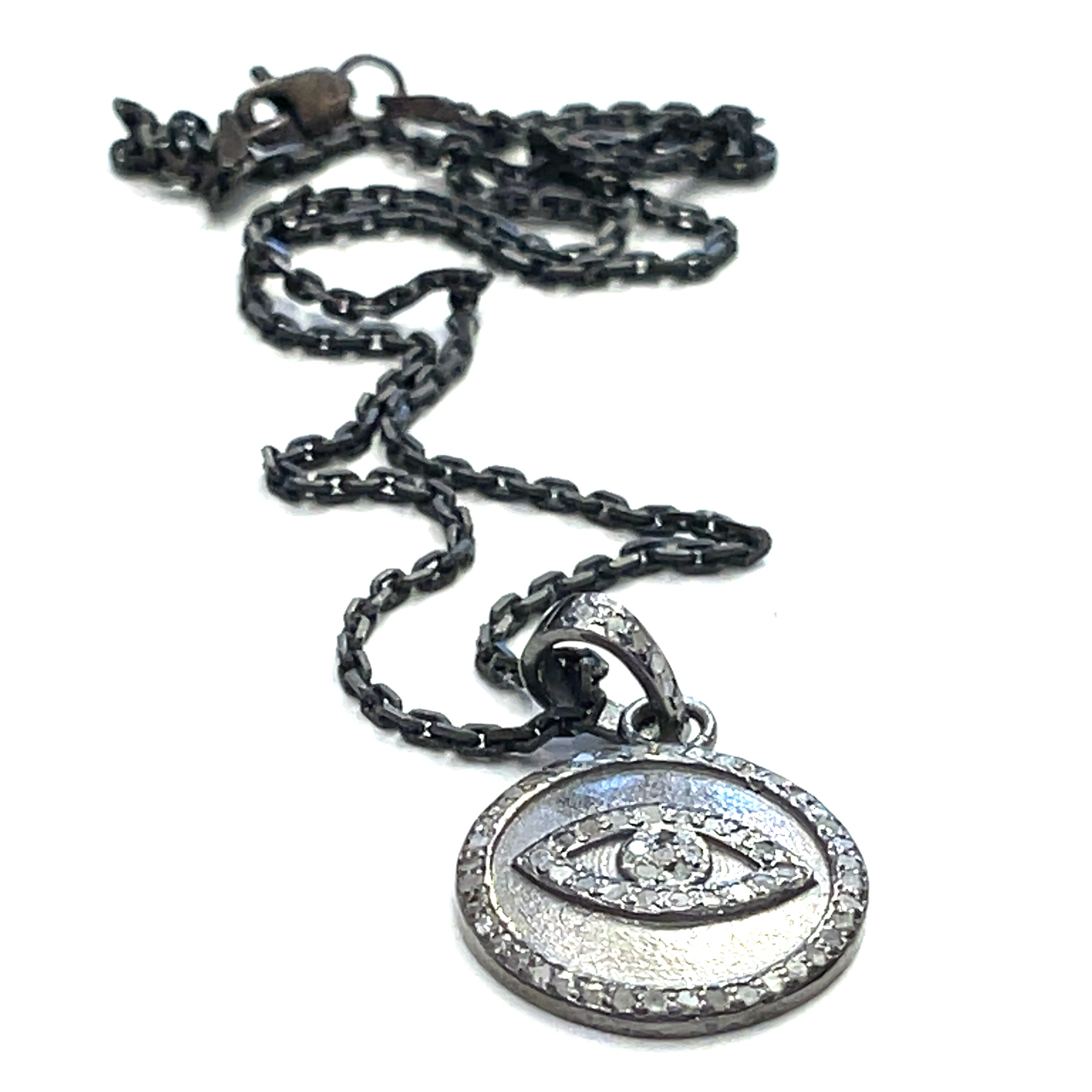 Close-up of diamond pavé Evil Eye pendant showing oxidized texture and detail on a white background flat center long overview.
