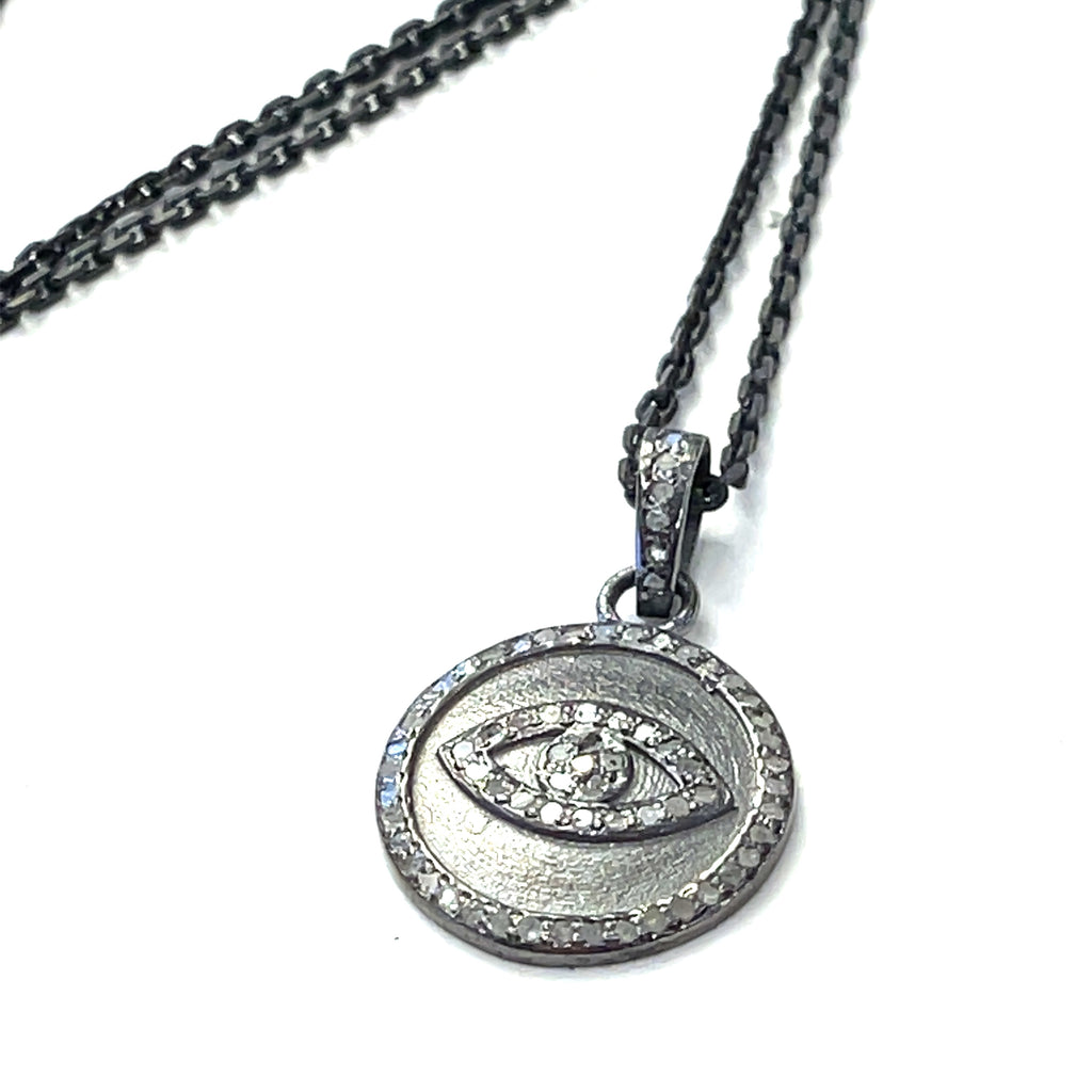 Close-up of diamond pavé Evil Eye pendant showing oxidized texture and detail on a white background flat center pendant overview.