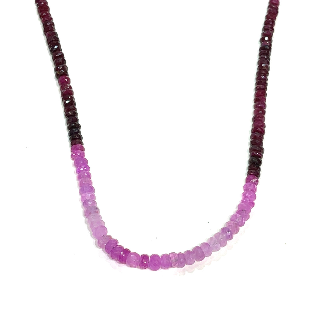 Close-up of faceted ruby roundel beads showing deep red brilliance. On a white background, front and center, a long hanging overview.