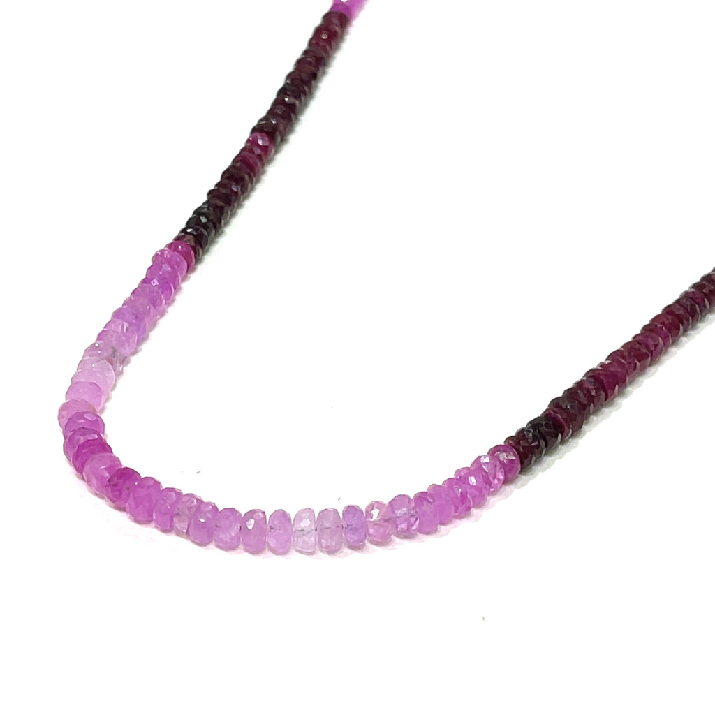 Close-up of faceted ruby roundel beads showing deep red brilliance. on a white background front, center long hanging overview.