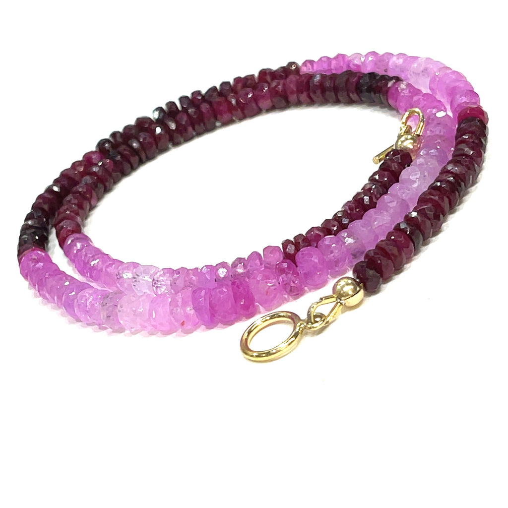 Close-up of faceted ruby roundel beads showing deep red brilliance. on a white background front, center spiral overview.