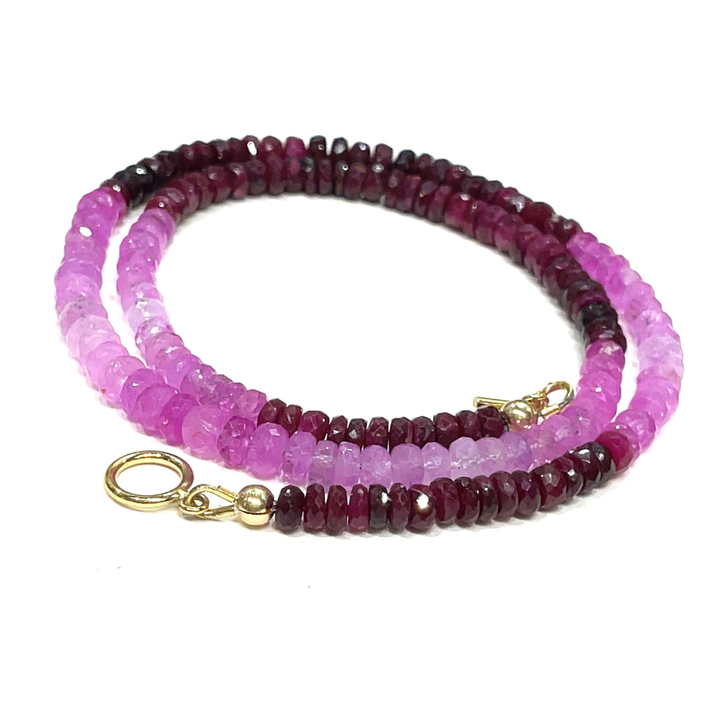 Close-up of faceted ruby roundel beads showing deep red brilliance. on a white background front, center spiral toggle overview.