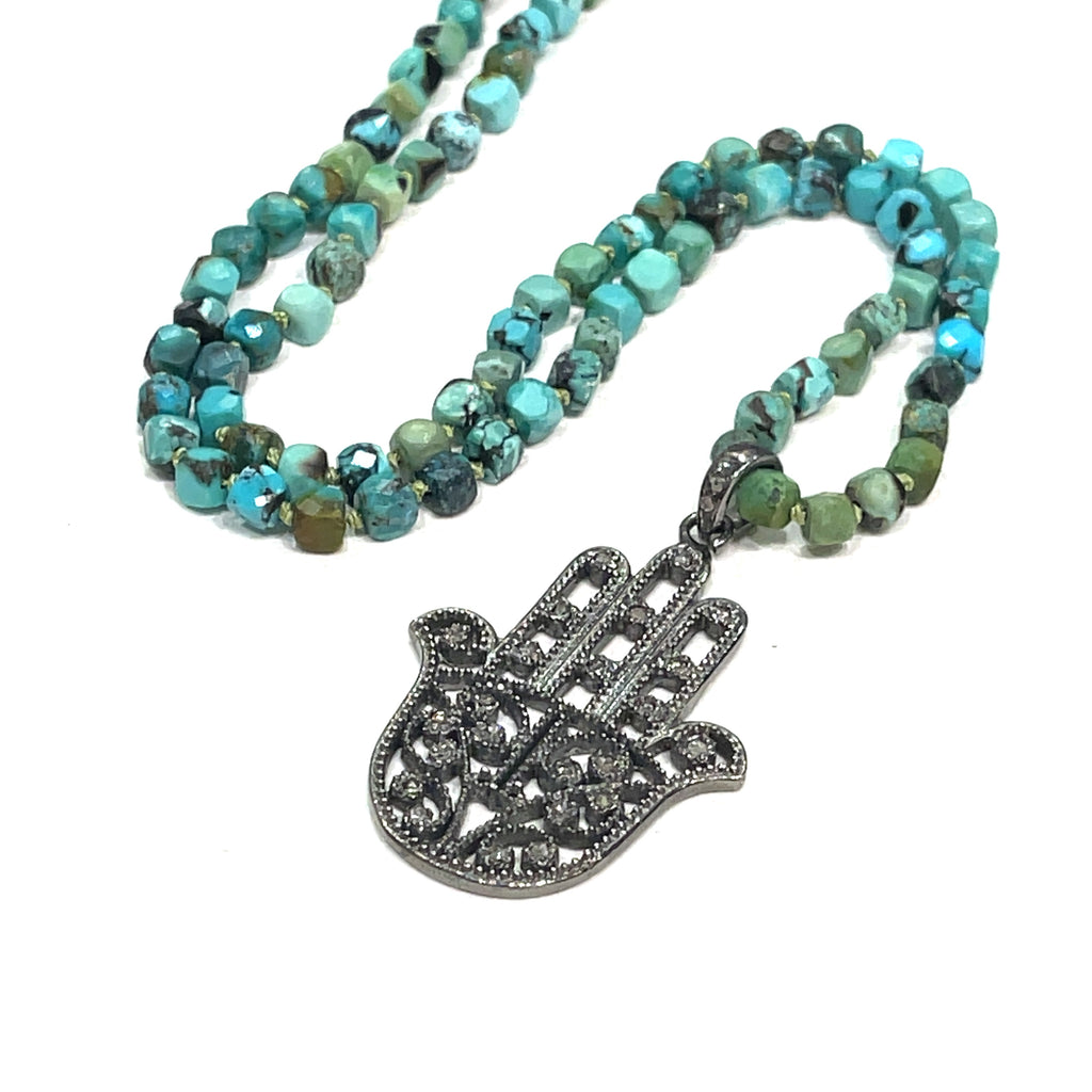 Close-up of faceted turquoise beads on silk cord with sterling silver toggle clasp on a white background overview.