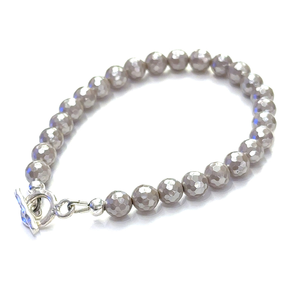 Close-up of iridescent Mother of Pearl beads showing natural shimmer and detail on a white background slight left back toggle overview.