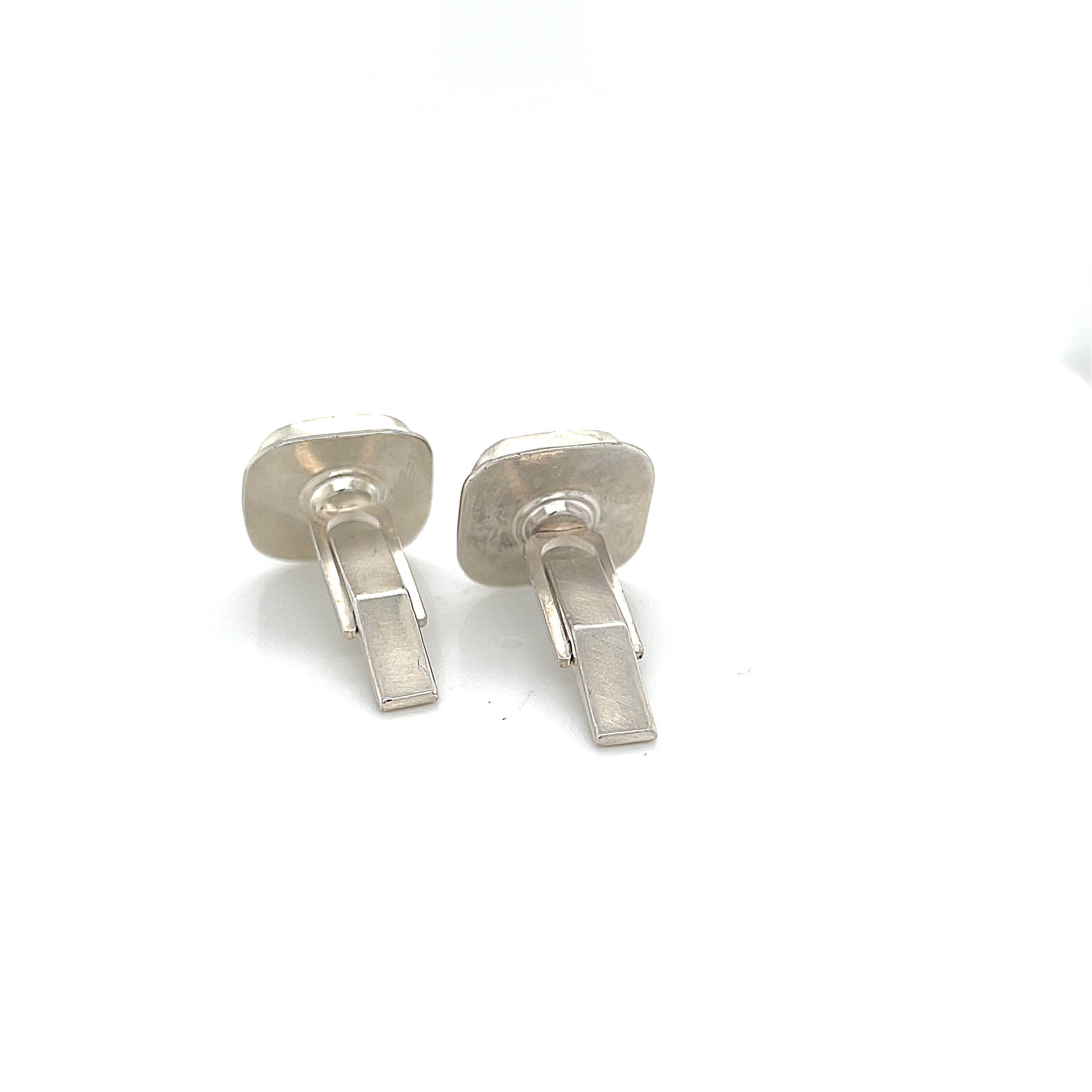 Close-up of natural quartz crystal, druzy texture, with brown inclusions, gemstone, with sterling silver cufflinks on a white background, back overview.
