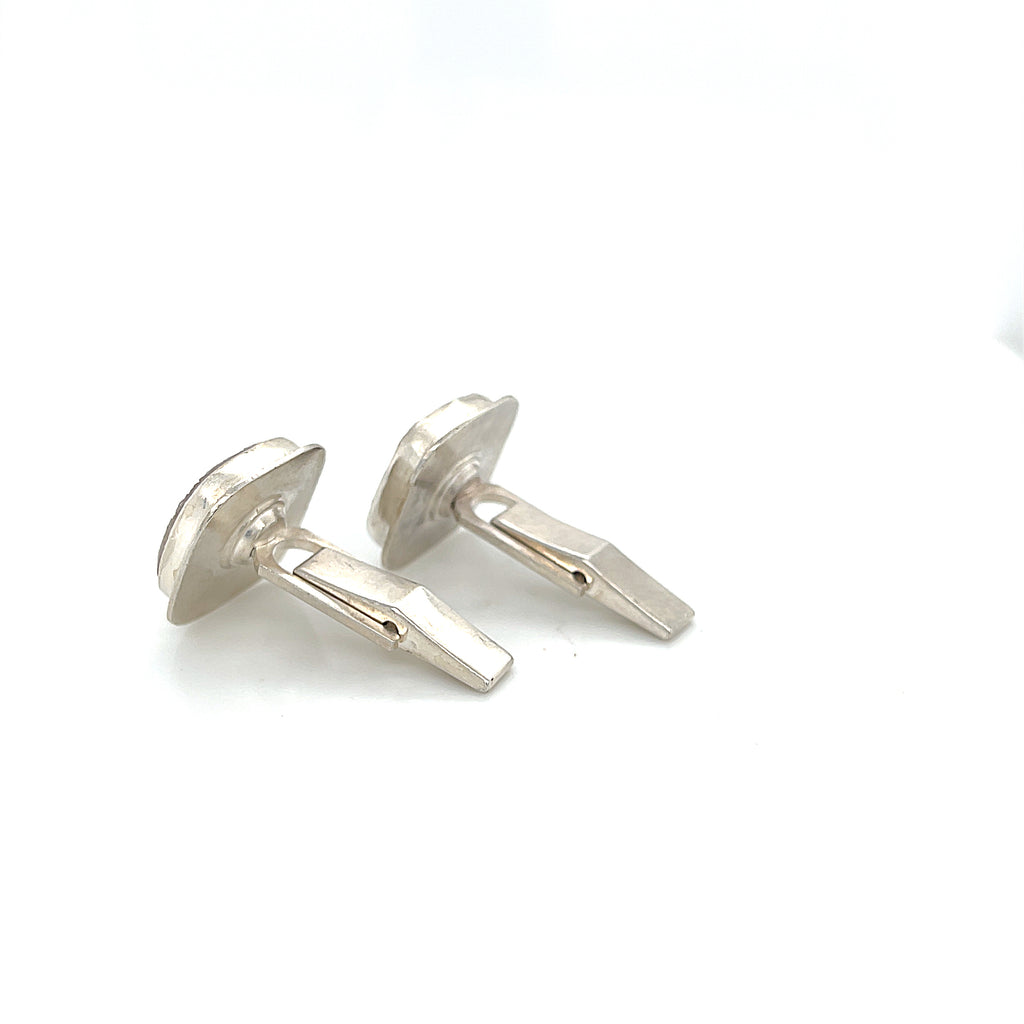 Close-up of natural quartz crystal, druzy texture, with brown inclusions, gemstone, with sterling silver cufflinks on a white background, back side  close up overview.