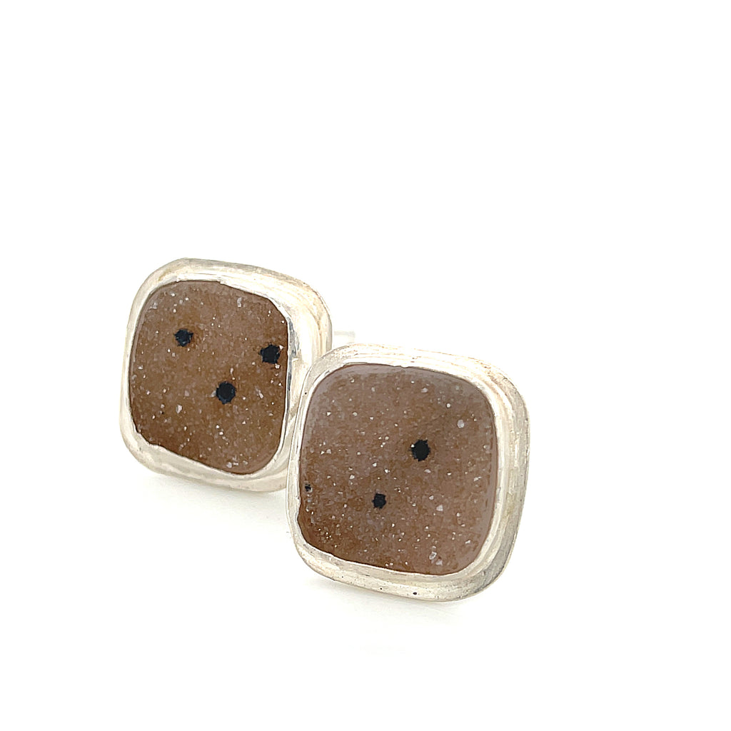 Close-up of natural quartz crystal, druzy texture, with brown inclusions, gemstone, with sterling silver cufflinks on a white background, front close up overview.