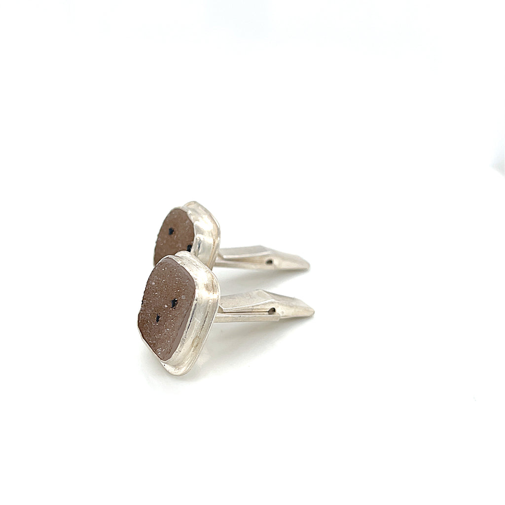 Close-up of natural quartz crystal, druzy texture, with brown inclusions, gemstone, with sterling silver cufflinks on a white background, right side  close up overview.