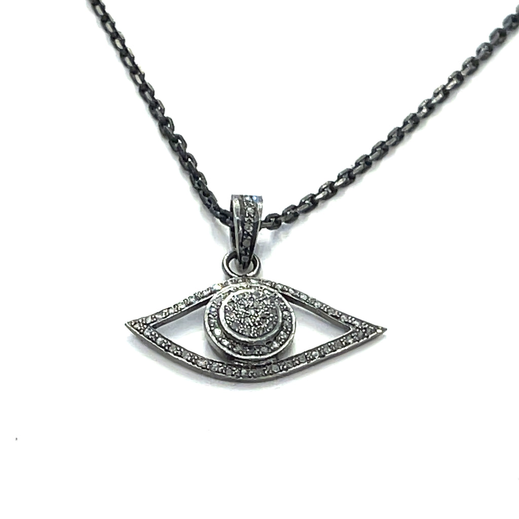 Close-up of pavé diamond Evil Eye pendant showing oxidized texture and sparkle on a white background center long hanging pendant close up overview.