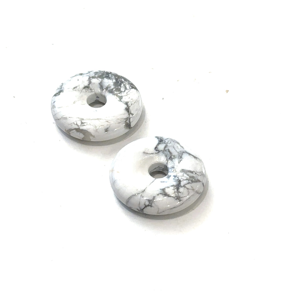 Close-up of polished gemstone donuts showing natural color and pattern variations on Howlite front overview on white background