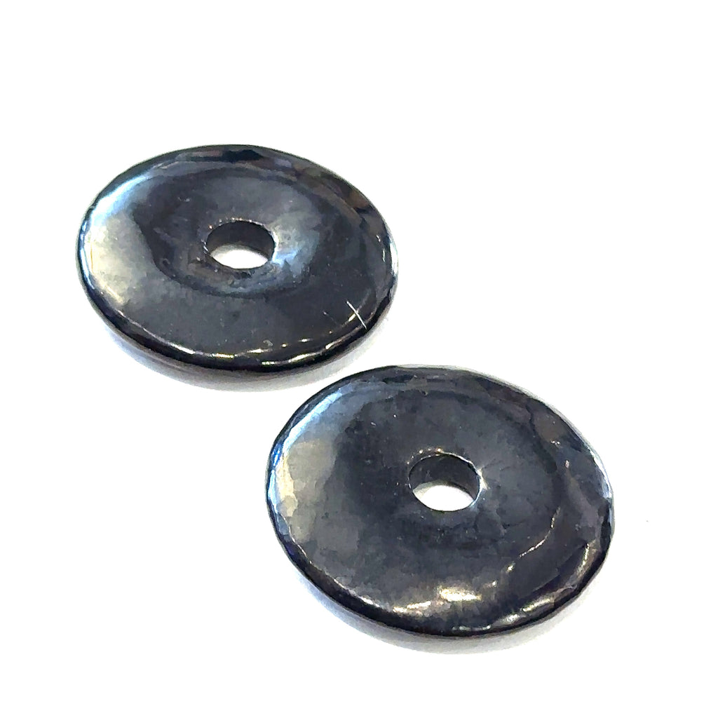 Close-up of polished gemstone donuts showing natural color and pattern variations on Shungite front overview on white background
