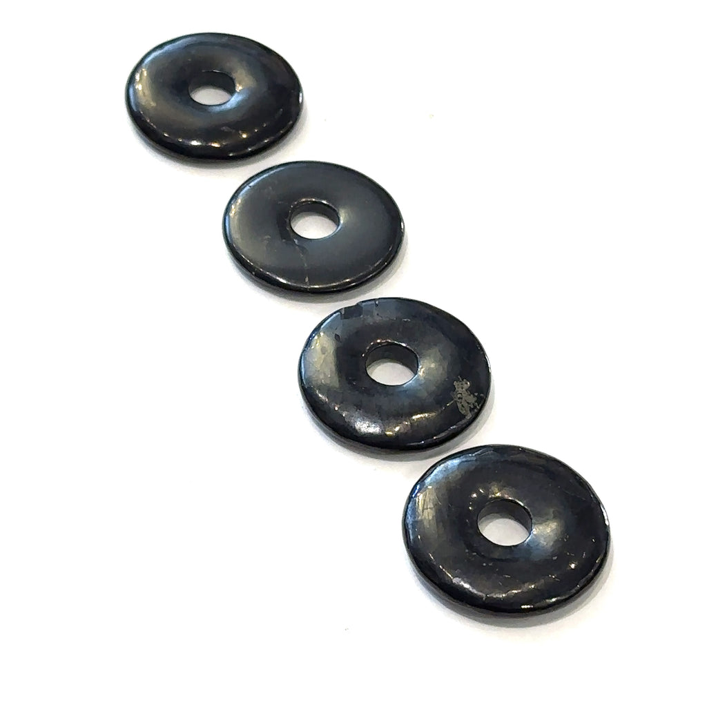 Close-up of polished gemstone donuts showing natural color and pattern variations on several Shungite  front overview on white background