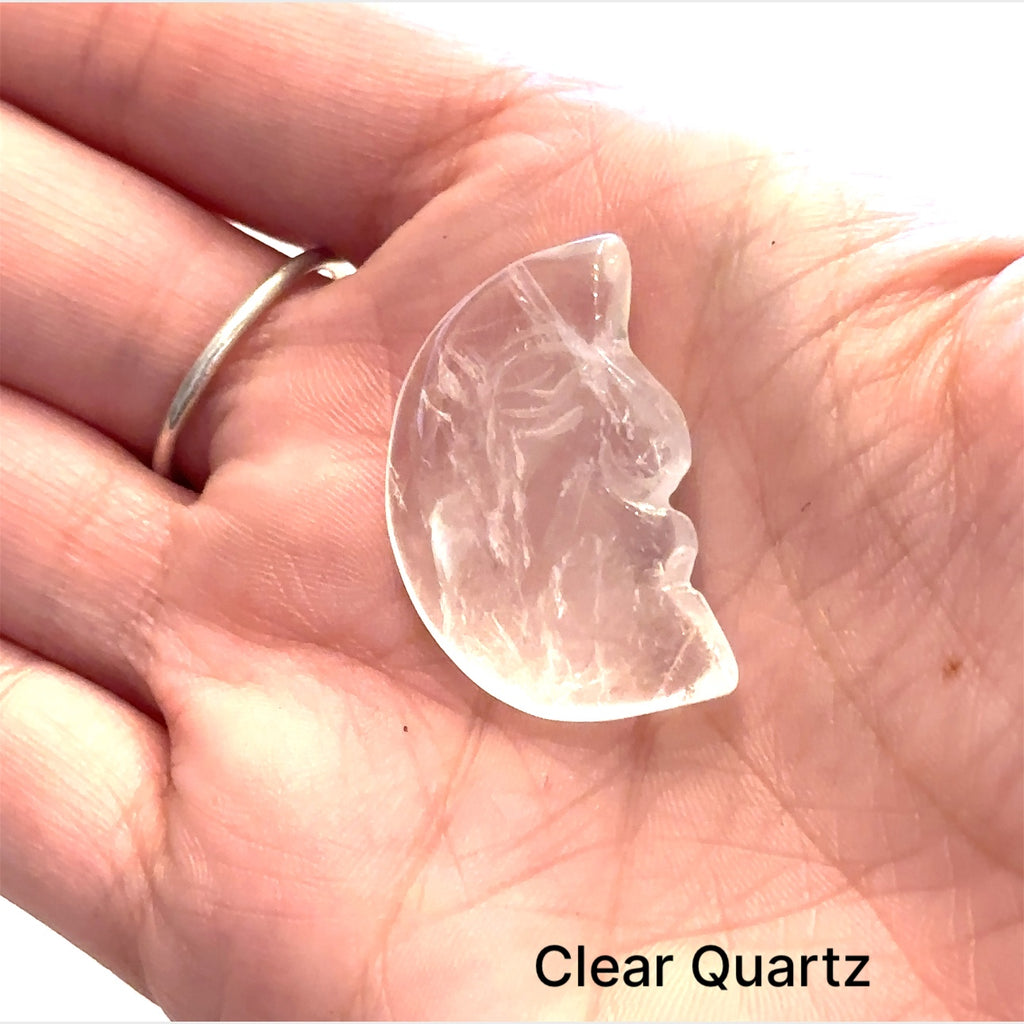 Close-up of polished moon-shaped  Clear Quartz gemstones  in models palm on a white background front overview