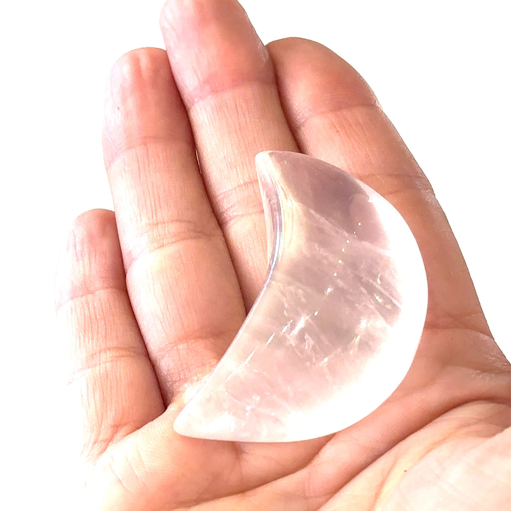 Close-up of polished moon-shaped  XL Rose Quartz gemstones in models palm  on a white background front overview