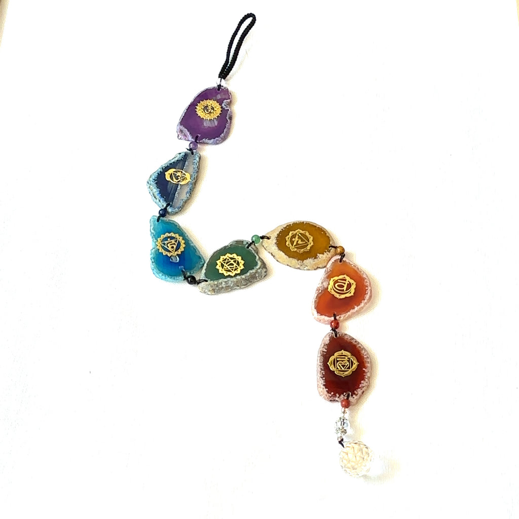 Colorful chakra crystal ornament with healing energy stones and crystal ball tassel on a white background long overview. 