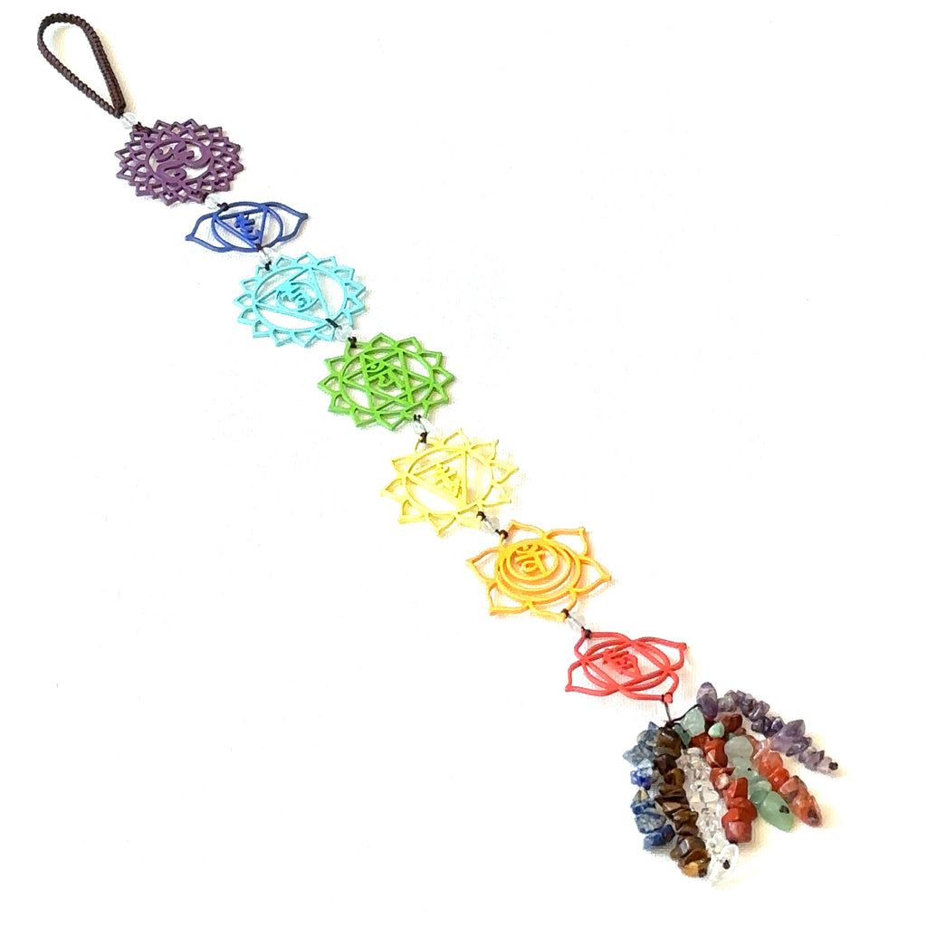 Colorful chakra metal ornament with healing energy stones and  gemstone tassel on a white background long overview. 