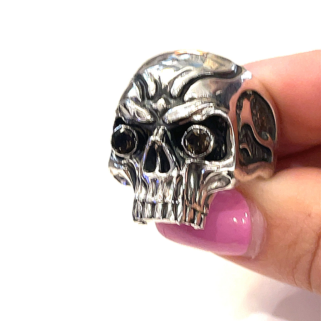 Custom CAD-designed silver skull ring — artisan men’s jewelry held in models finger tips on a white background front view