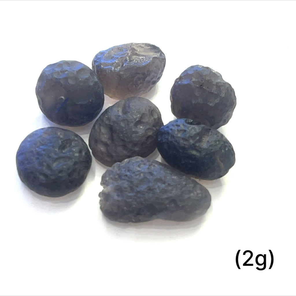 Detailed shot of authentic Colombianite obsidian “Piedra Rayo” gemstone sizes (2g) on white background overview.