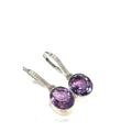 Gemstone Amethyst faceted ovals in a sterling silver bezel with CZ's lever back earrings on a white background right angled overview. 