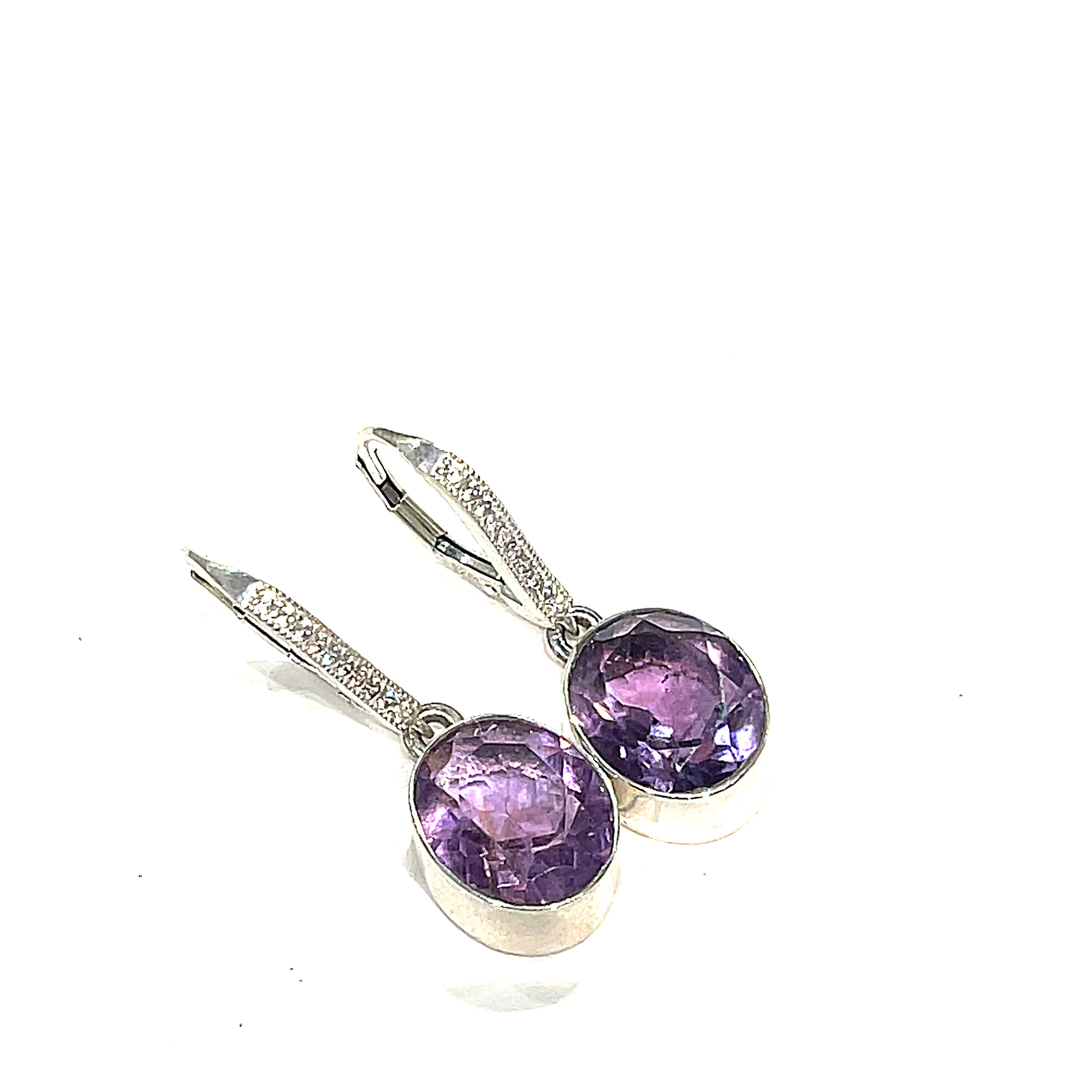 Gemstone Amethyst faceted ovals in a sterling silver bezel with CZ's lever back earrings on a white background right angled overview. 