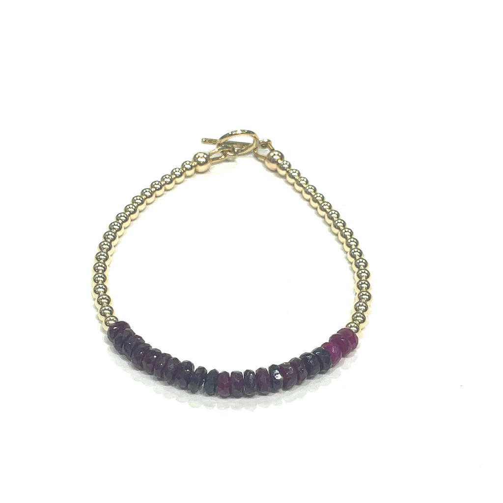 Genuine Ruby gemstone beaded bracelet with gold-filled toggle clasp by Hidden Jewel on a white background front view. 