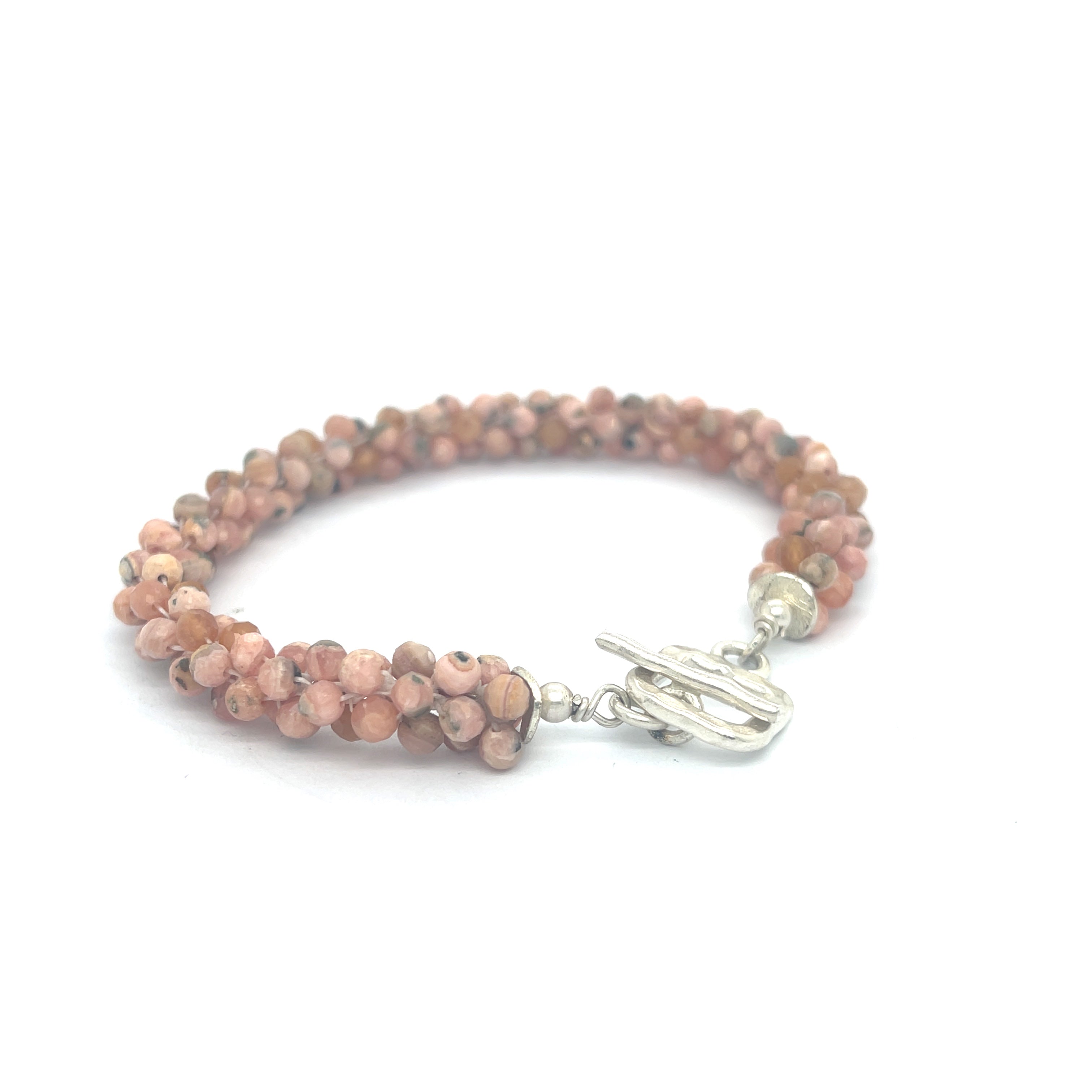 Hand-crocheted Rhodochrosite gemstone bracelet with sterling silver  toggle clasp on a white background back left angle overview.