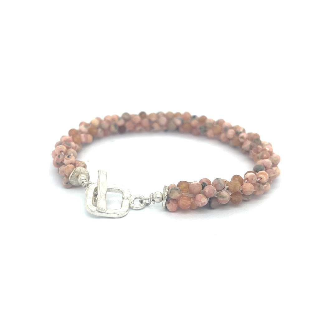 Hand-crocheted Rhodochrosite gemstone bracelet with sterling silver  toggle clasp on a white background back toggle left angle overview.