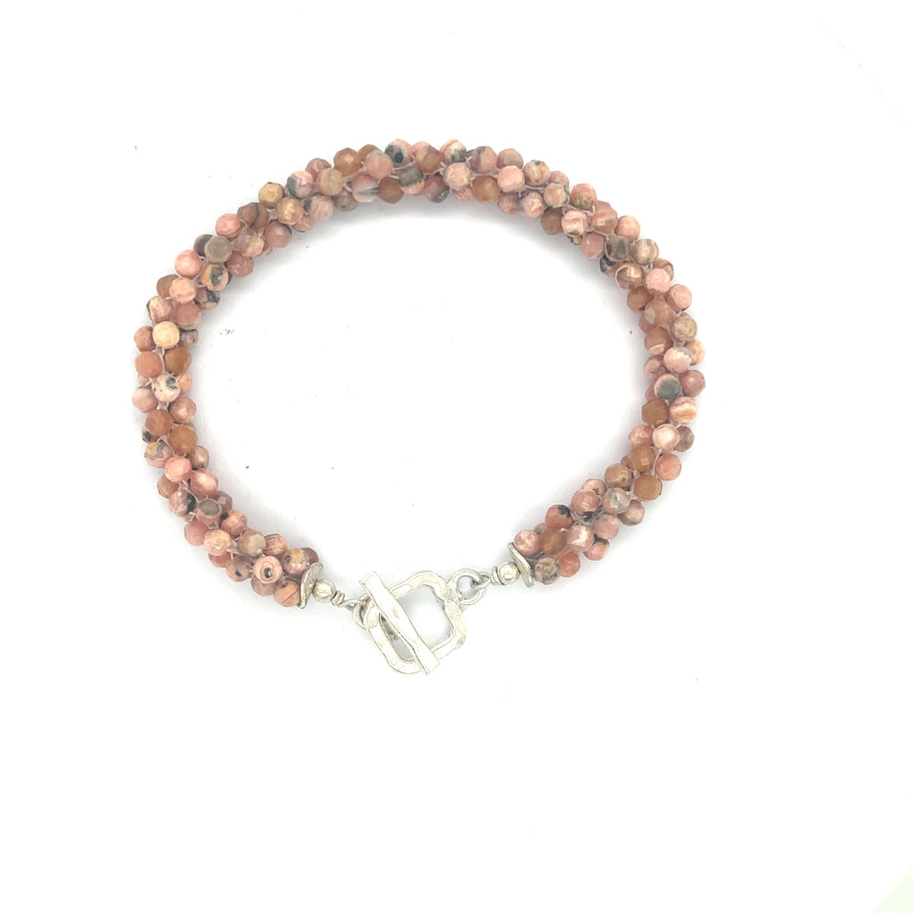 Hand-crocheted Rhodochrosite gemstone bracelet with sterling silver  toggle clasp on a white background center overview.