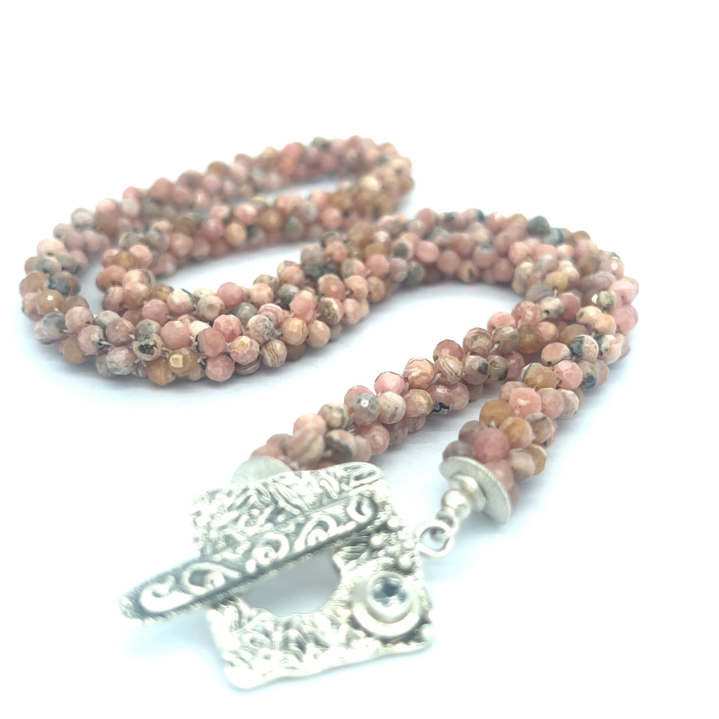 Hand-crocheted Rhodochrosite gemstone necklace with sterling silver toggle and Blue Topaz accent – Hidden Jewel of the South End on a white background, a long center toggle close up overview. 
