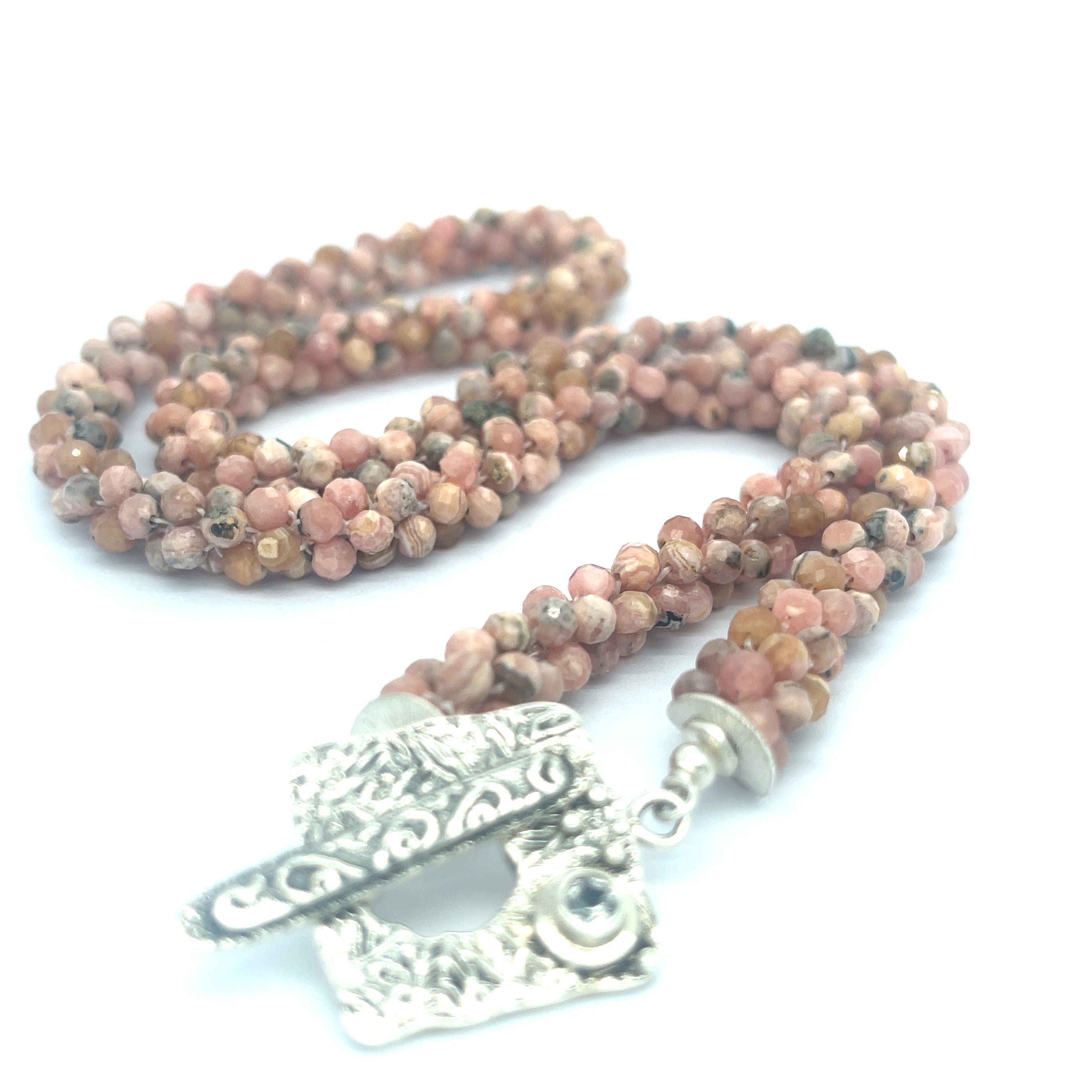 Hand-crocheted Rhodochrosite gemstone necklace with sterling silver toggle and Blue Topaz accent – Hidden Jewel of the South End on a white background, a long center toggle close up overview. 
