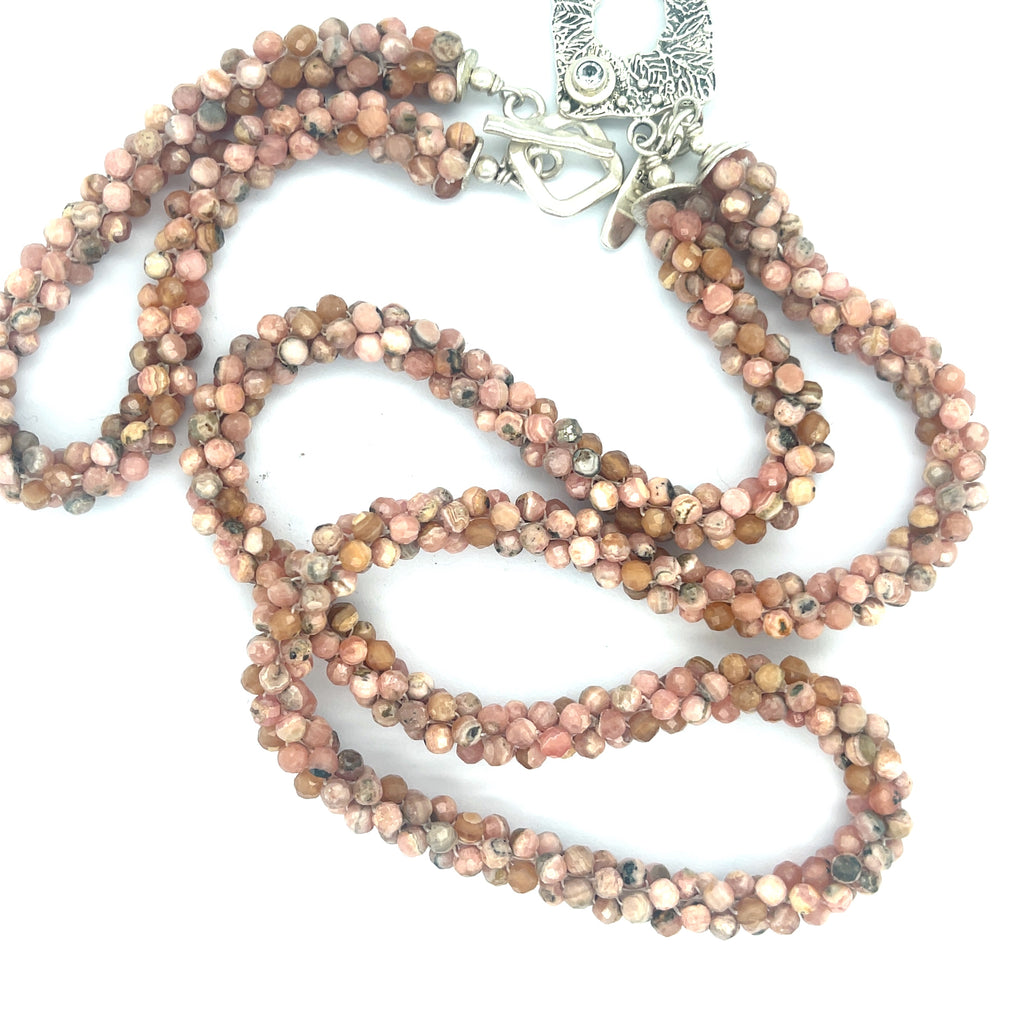 Hand-crocheted Rhodochrosite gemstone necklace with sterling silver toggle and Blue Topaz accent toggle with its matching bracelet  on a white background, a long center close up overview. 