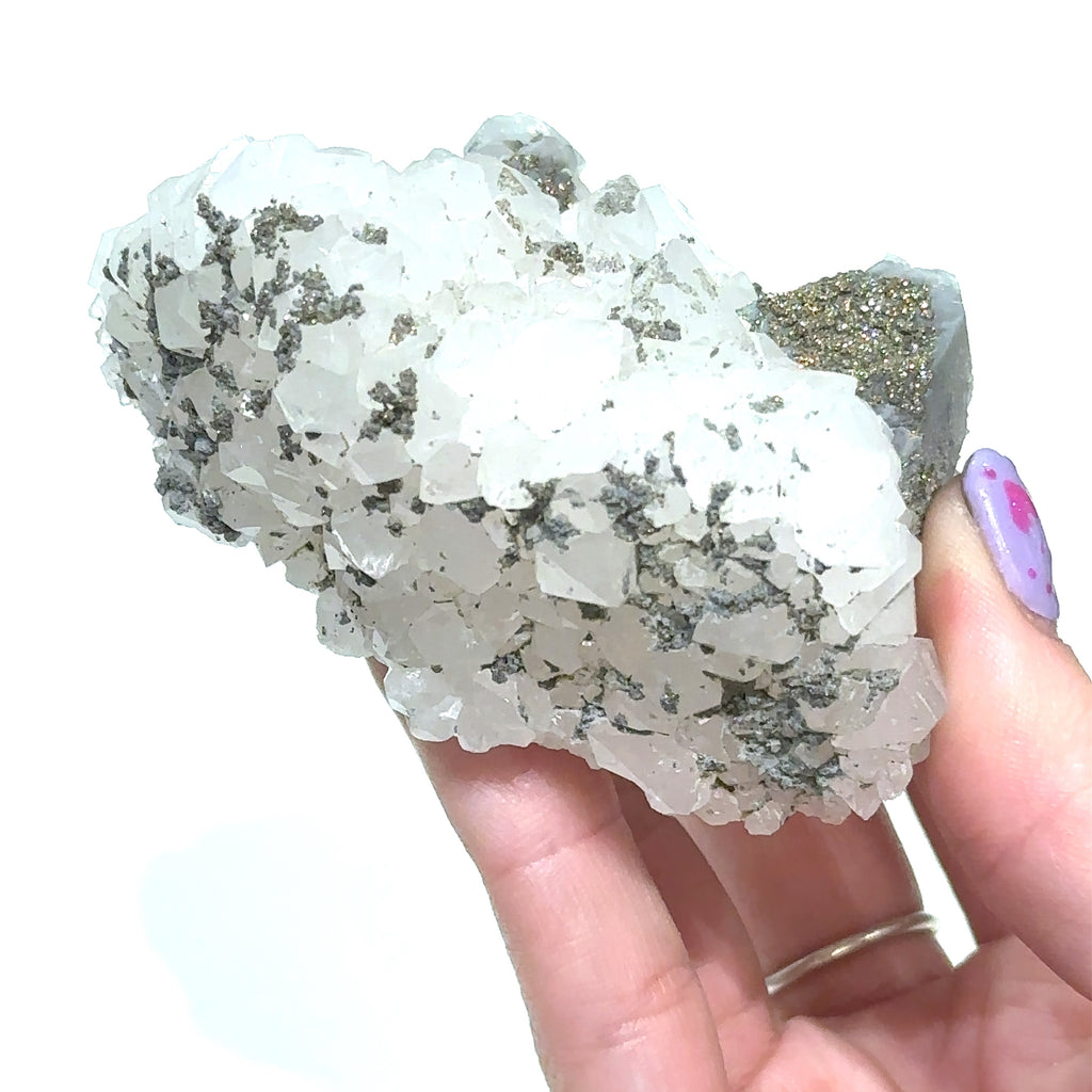 Hand holding Calcite over Fluorite with Pyrite crystal cluster in natural light on white background front view