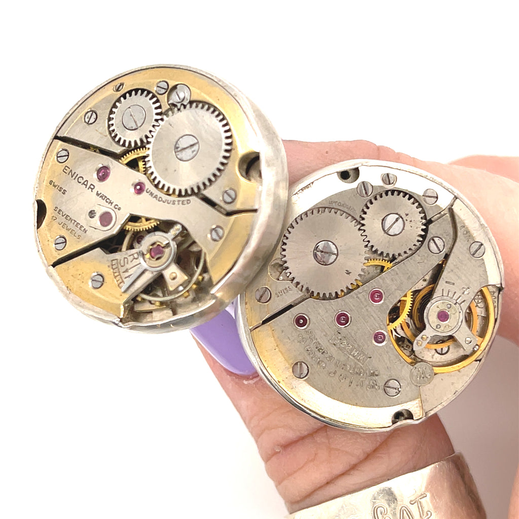 Handcrafted antique watch movement cuff links in sterling silver on a white background close up front  overview in the models finger tips. 