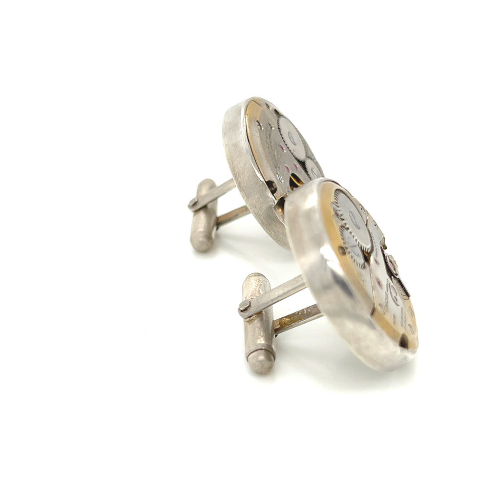 Handcrafted antique watch movement cuff links in sterling silver on a white background front  slight right angle overview. 