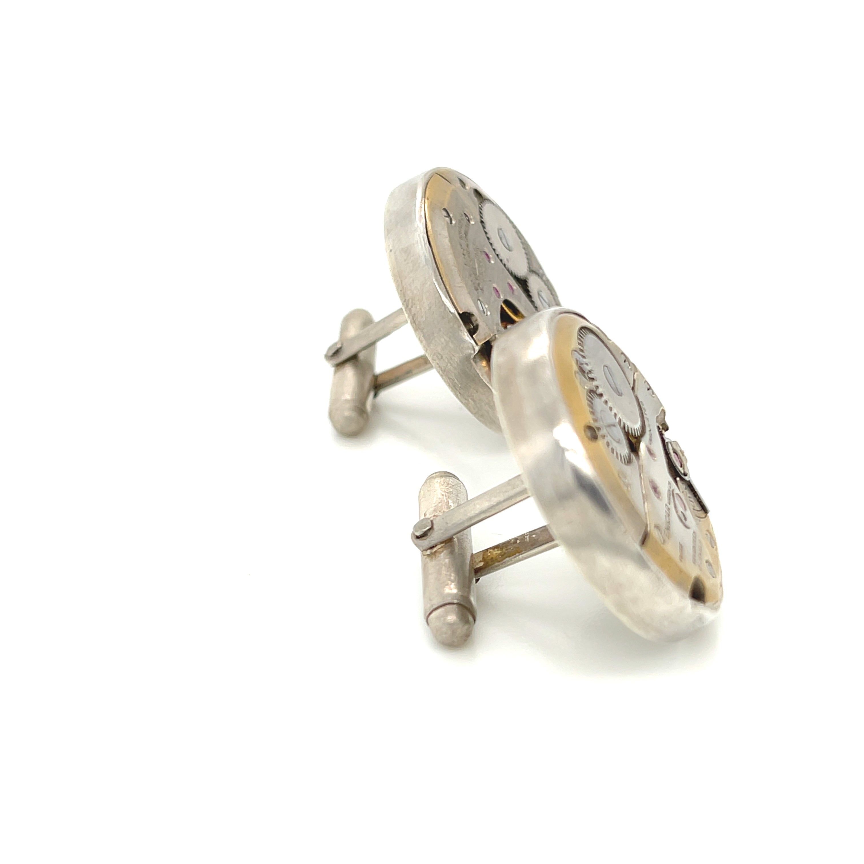 Handcrafted antique watch movement cuff links in sterling silver on a white background front  slight right angle overview. 