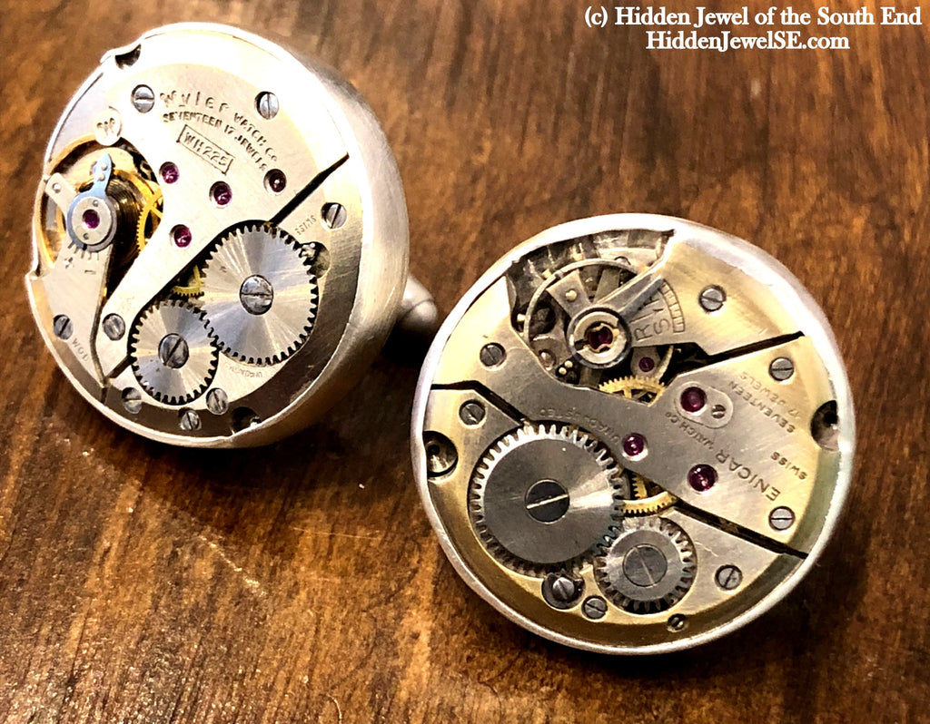 Handcrafted antique watch movement cuff links in sterling silver on a wood background close up front overview.