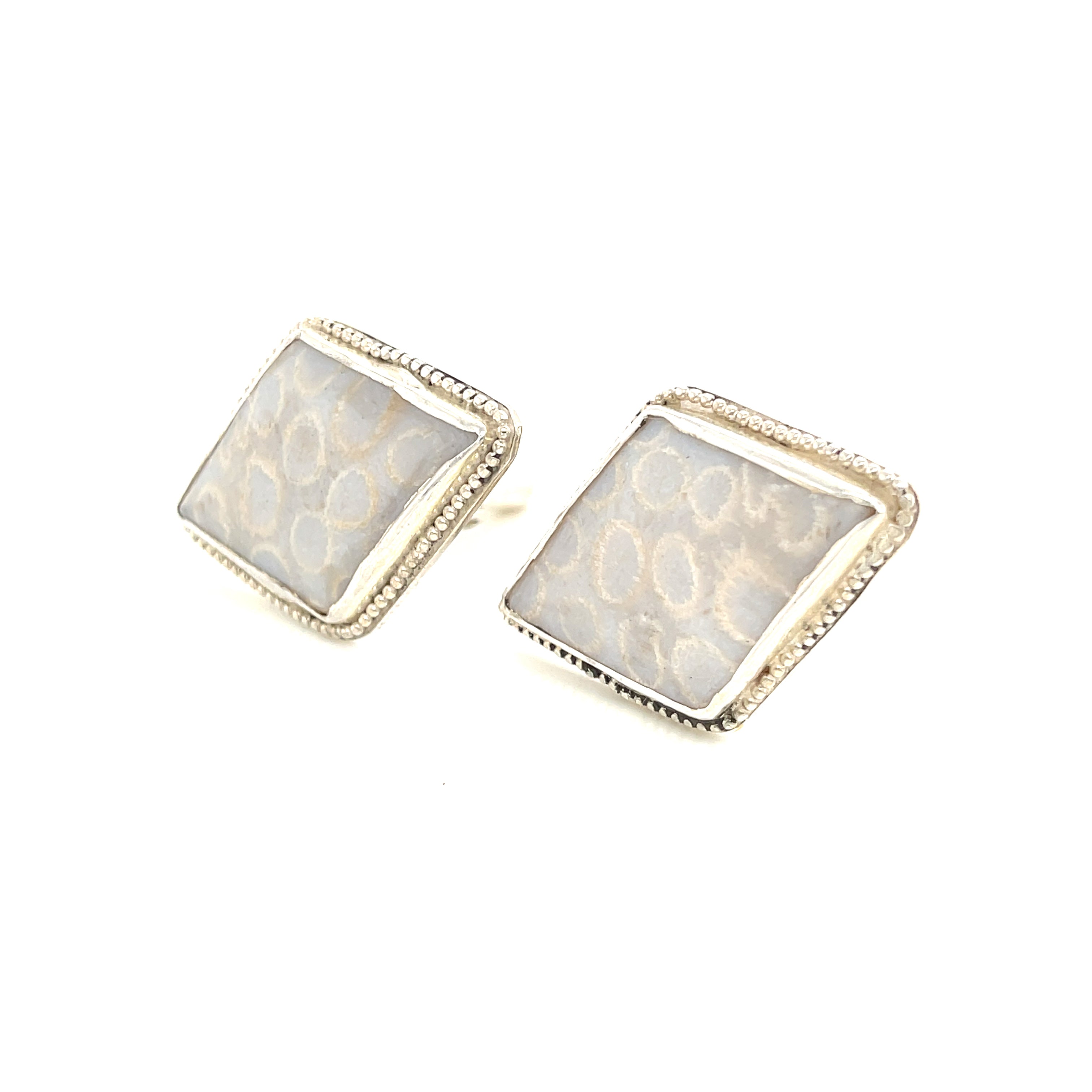 Handcrafted sterling silver fossil coral cuff links with beaded wire design on a white background slight left angle front view.