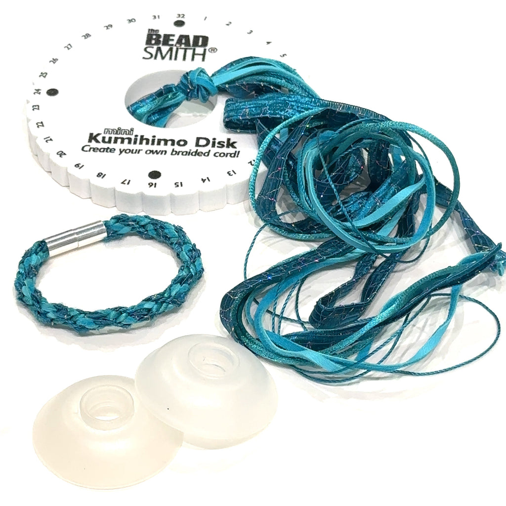 Kumihimo teal bracelet kit with disk, bobbins, cord, and clasp displayed neatly on table with white background overview