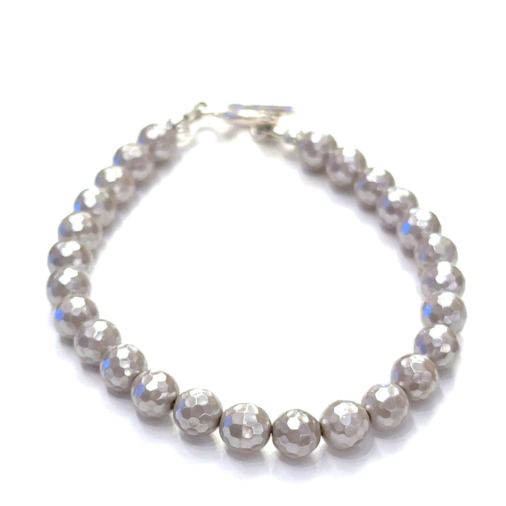 Mother of Pearl gemstone bracelet with faceted 6mm beads and sterling silver hammered toggle clasp handmade by Hidden Jewel. on a white background front center overview.