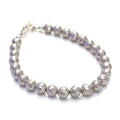 Mother of Pearl gemstone bracelet with faceted 6mm beads and sterling silver hammered toggle clasp handmade by Hidden Jewel. on a white background slight right angle overview.