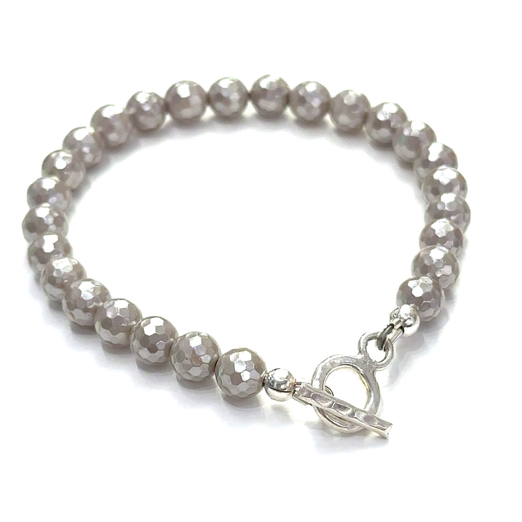 Mother of Pearl gemstone bracelet with faceted 6mm beads and sterling silver hammered toggle clasp handmade by Hidden Jewel. on a white background toggle view.